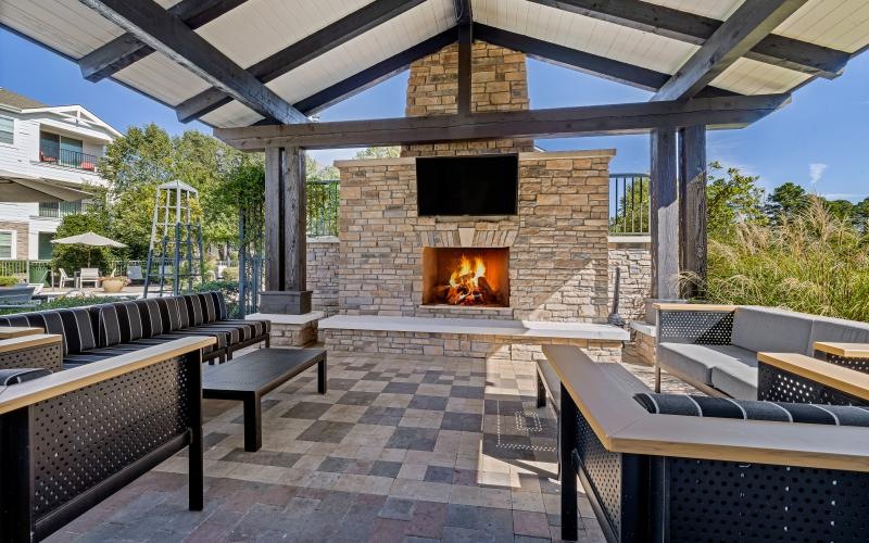 an outdoor lounge area with couches, chairs and a fireplace